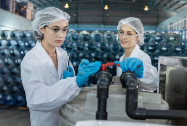 Female worker checking quality valve On and Off water production Female worker checking quality valve On and Off water production line of factory. management system before process of filling water into bottles. Drinking water product industry.