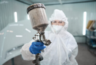 Painting master with a paint injection tank in her hands Painting master with a paint injection tank in her hands, she is in the paint shop