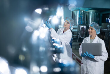 Portrait of a scientist in the drinking water factory using a la Portrait of a scientist in the drinking water factory using a ladder, looking at the water tanks above and examining with a colleague's laptop